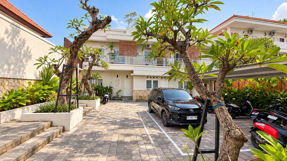 Front of the property with parking and frangipani trees